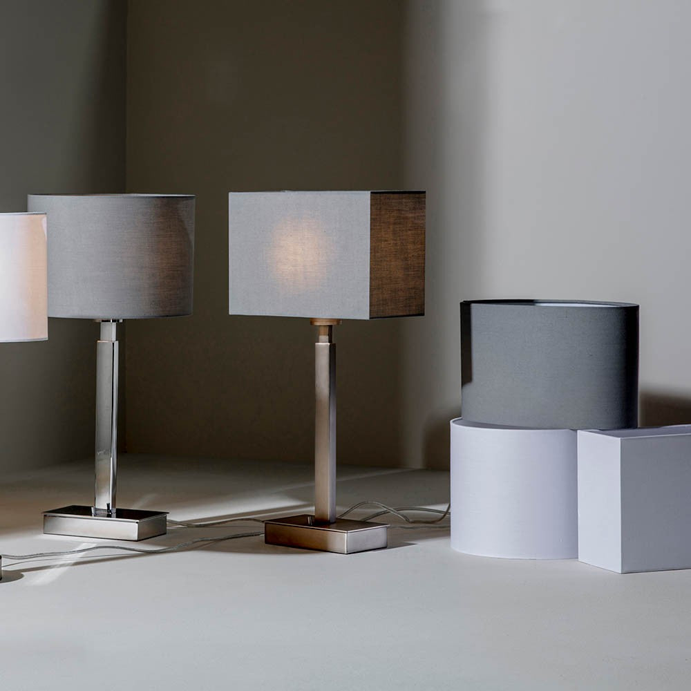 Chartstead Rectangular 27cm Tapered Lamp Shade in grey fabric, shown fitted to a table lamp alongside matching shades in a room setting.