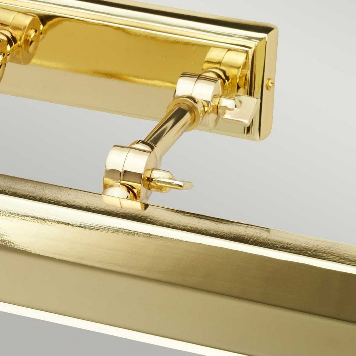 Close-up of the adjustable hinge mechanism from the Chawton Large Picture Light in Polished Brass, attached to a rectangular base. The hinge includes a small knob, and the reflective metal surface is highlighted against a neutral background, echoing the quality found in Chawton designs.