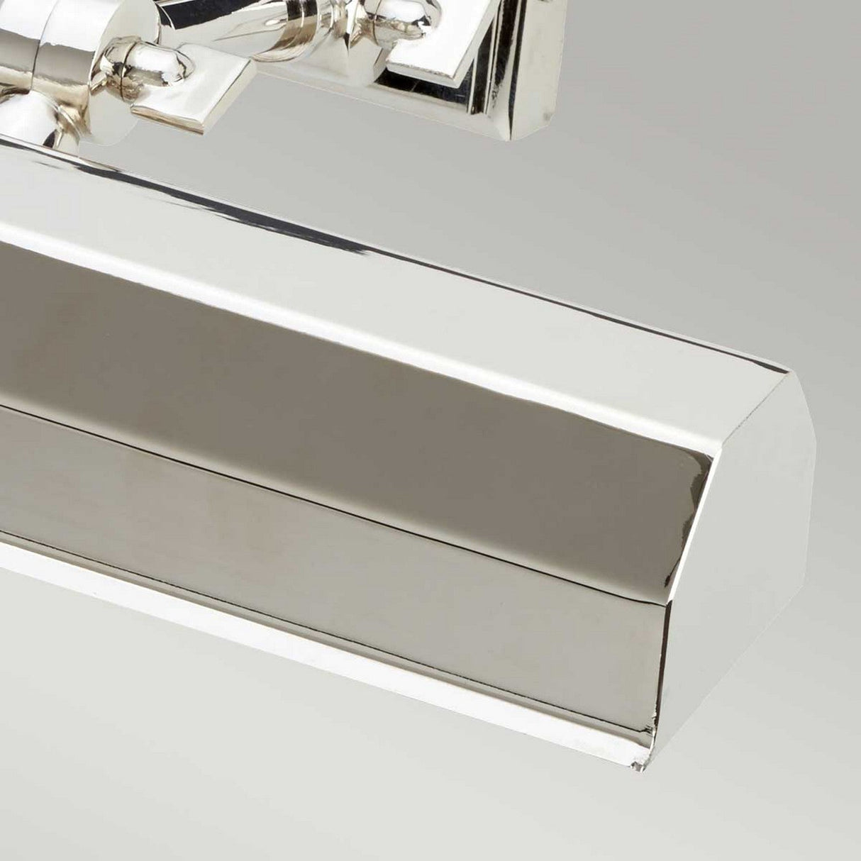 Close-up of a sleek and modern Chawton Medium Picture Light - Polished Nickel with an angular design against a plain gray background. Its adjustable knuckle joints and smooth metallic surface reflect light beautifully, highlighting its polished finish.