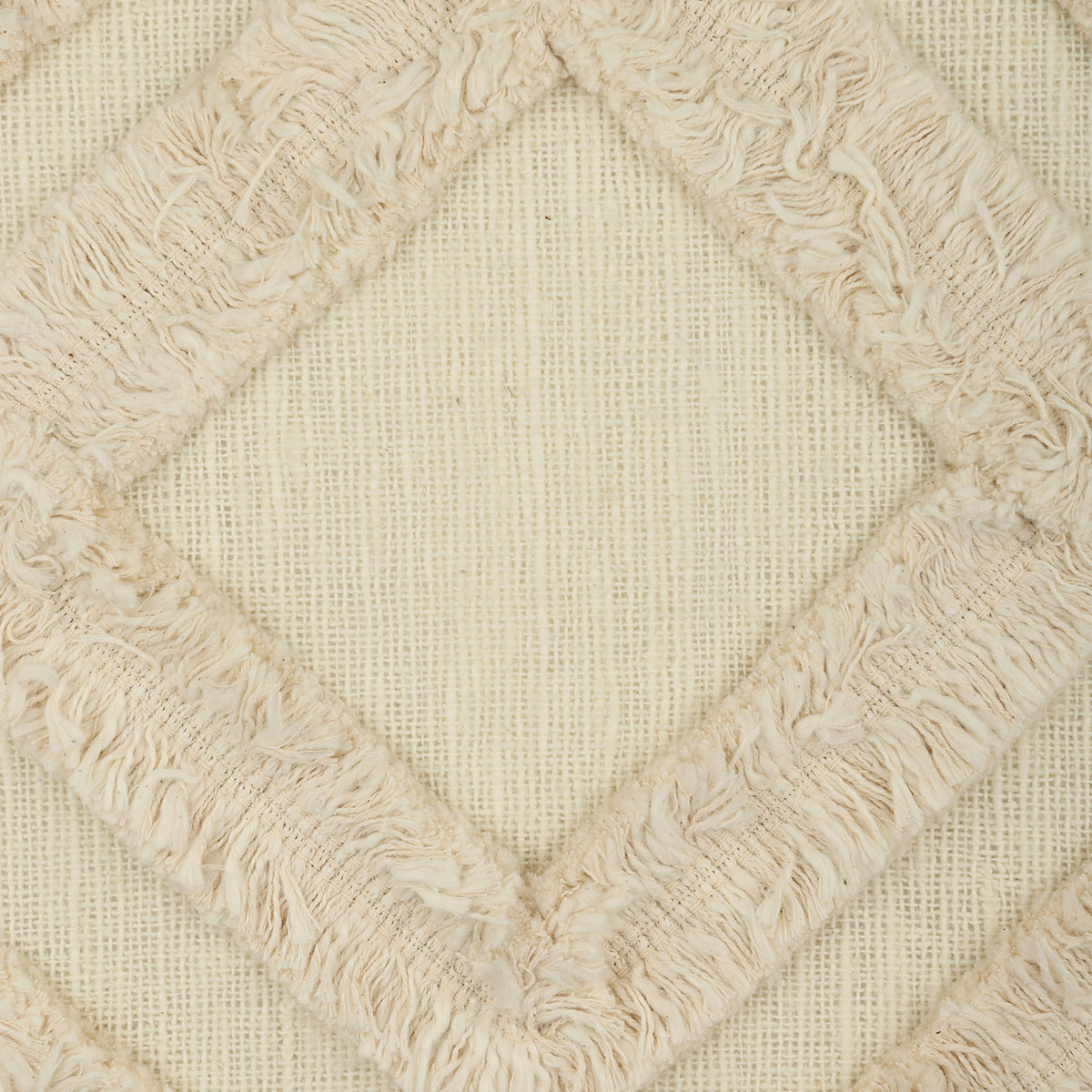 Chevery Cushion in cream cotton, close-up of the textured weave with a tufted, fringed diamond pattern raised across the fabric.
