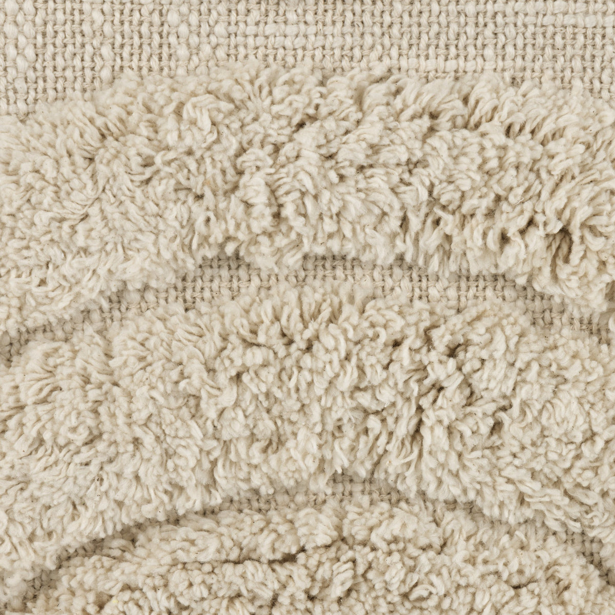 Close-up of the Chevery cushion in natural cream cotton, showing a tufted arc pattern against a loosely woven, slubby flat-weave fabric.
