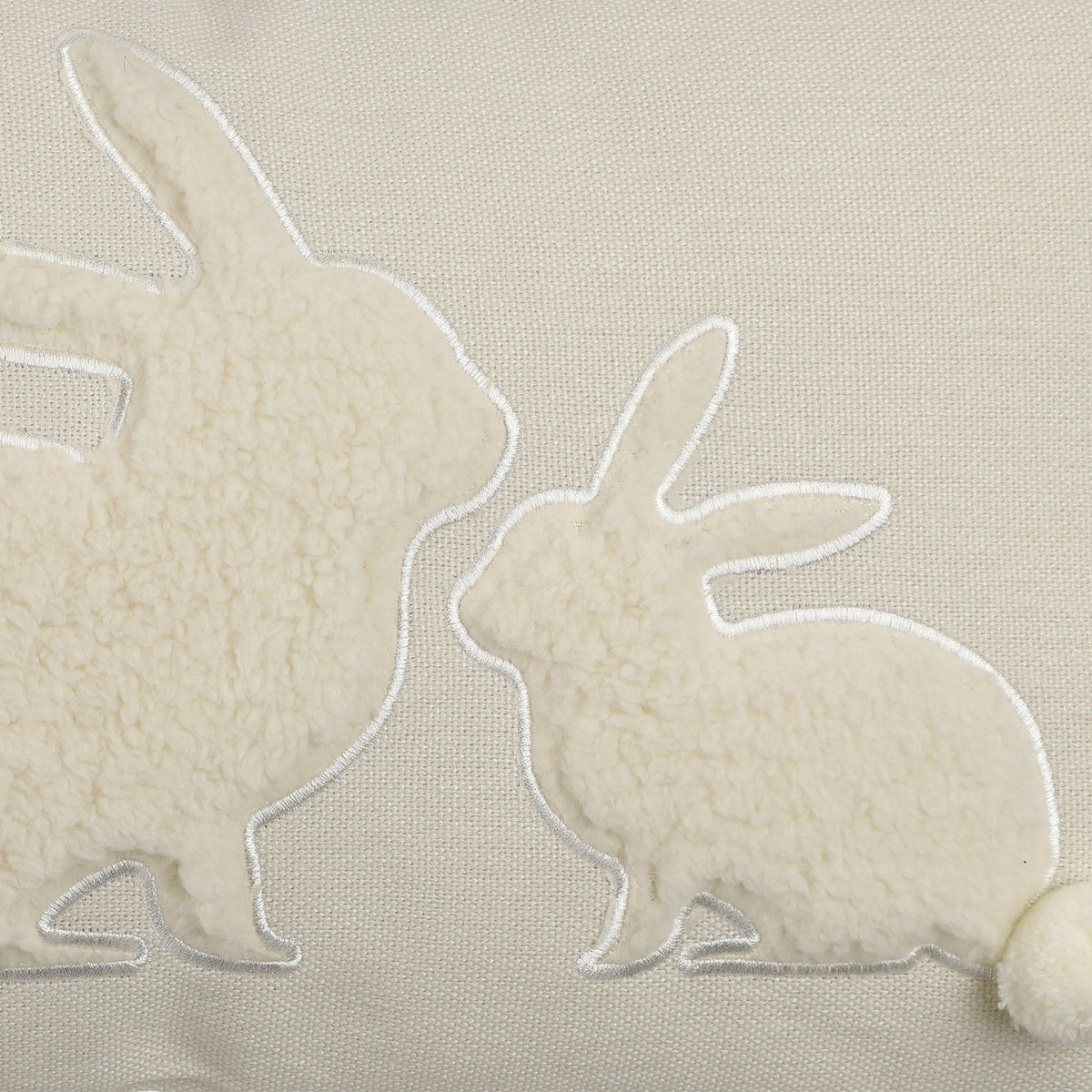 Chevery rectangular cushion in natural woven cotton with two nose-to-nose rabbits in curly sherpa fleece, white stitched outlines, and pompom tails.