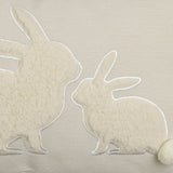 Chevery rectangular cushion in natural woven cotton with two nose-to-nose rabbits in curly sherpa fleece, white stitched outlines, and pompom tails.