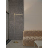 Minimalist living room with a beige tufted sofa, white coffee table, large window by a gray textured wall, and the Cinto Dimmable LED Floor Lamp 20W 3000K in antique brass—ideal for contemporary interiors.