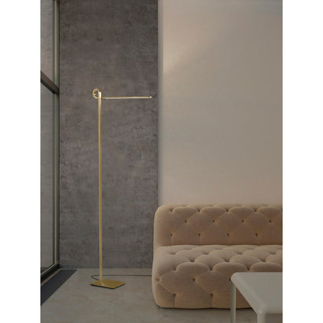 Minimalist living room with a beige tufted sofa, white coffee table, large window by a gray textured wall, and the Cinto Dimmable LED Floor Lamp 20W 3000K in antique brass—ideal for contemporary interiors.