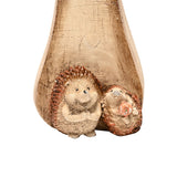 Resin mushroom ornament with a pale wood-effect stem and two brown hedgehog figures nestled at its base, shown against a plain white background.