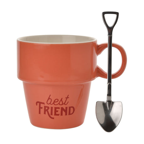 Orange glazed ceramic mug shaped like a plant pot with cream interior, loop handle, and "best FRIEND" text, shown with a spade-handled spoon on a white background.