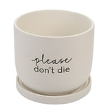 White round ceramic plant pot with matching saucer, matte finish, printed with "please don't die" in black script and lowercase text, on a plain background.