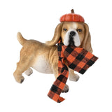 Resin garden ornament of a standing beagle in tan brown with white chest and paws, wearing an orange pumpkin hat and an orange-and-black check scarf, on a plain white background.