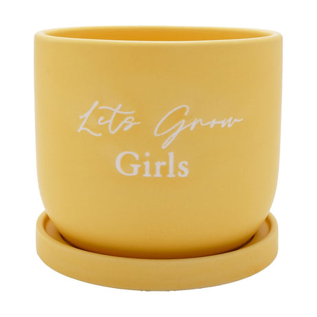 Round ceramic planter in soft yellow with "Lets Grow Girls" in white script, smooth curved sides, shown with a matching round saucer on a plain white background.