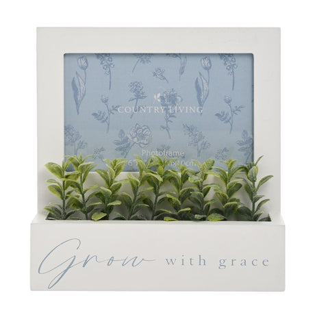 White MDF photo frame with landscape opening and base planter trough of green leafy stems, text "Grow with grace" on front, plain white background.