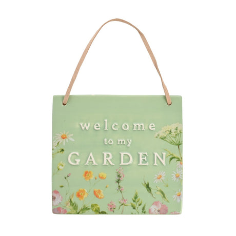 Square ceramic hanging plaque in olive green with white "welcome to my GARDEN" text, bordered by painted wildflowers and a tan suede hanging strap, shown on a plain white background.