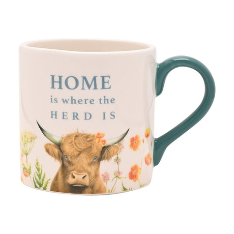 White ceramic mug with teal handle, featuring a highland cow among wildflowers and "HOME is where the HERD IS" text, shown on a plain white background.