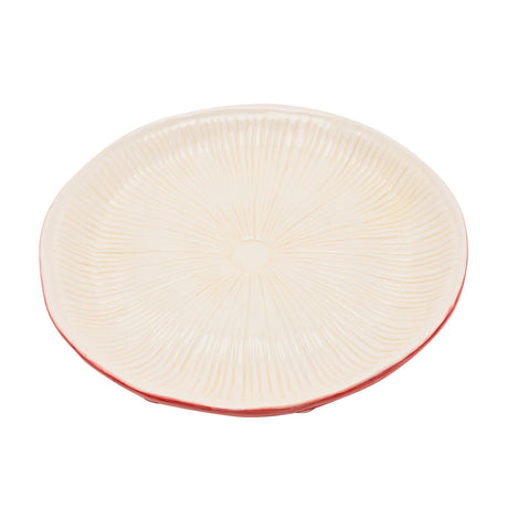 Round ceramic dinner plate with cream, gill-textured top radiating from a centre point and a red rimmed edge, styled as a toadstool cap, on a plain white background.