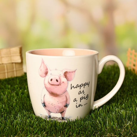 White earthenware mug with a pink glazed interior, printed with an illustrated pig and "happy as a pig in..." script, shown outdoors on grass.
