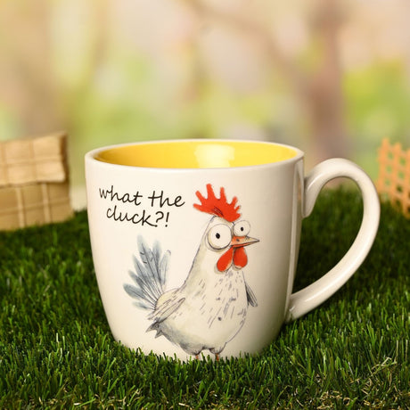 White earthenware mug with yellow interior, featuring a cartoon rooster illustration and "What the cluck?!" text, set outdoors on grass.