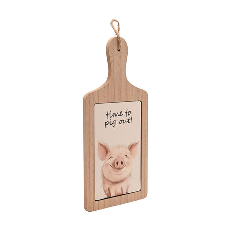 Paddle-shaped serving board with wood-look brown frame and rounded handle, featuring a cream ceramic tile with a smiling pig illustration and "time to pig out" script, shown on a white background.