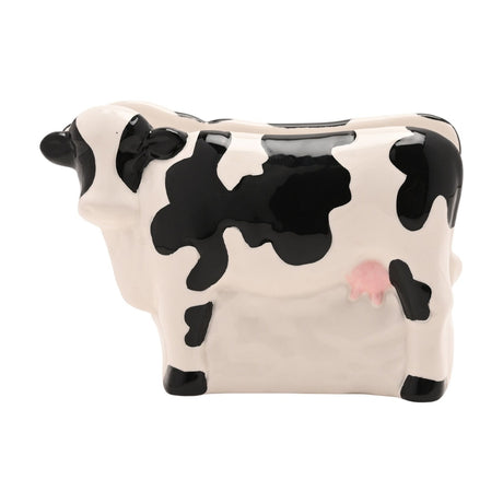 Standing Spotted Cow Stoneware Napkin Holder in white and black, glossy ceramic cow shape with black ears, hooves and patches, pink udder detail, on a plain white background.