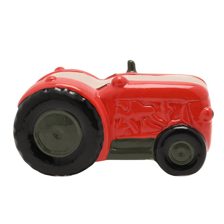 Tractor-shaped stoneware napkin holder in glossy red with black tyres, grey-green hubs, embossed bonnet detailing, and exhaust pipe, shown against a plain white background.