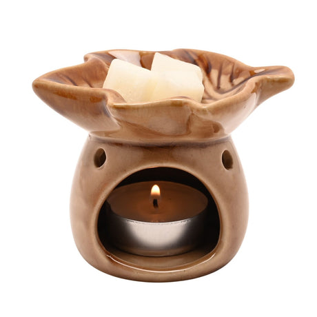 Autumn Leaf glazed ceramic wax melt burner in brown, with a leaf-shaped top dish holding wax cubes and a lit tealight in the arched base, on a white background.