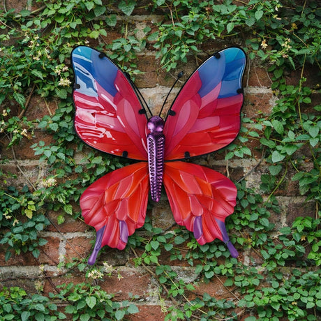 Butterfly Metal Wall Art, 45cm, with purple body and antennae, red and pink wings shading to blue tips, mounted on a brick wall surrounded by green ivy.