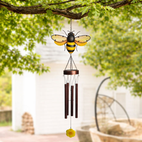 Bee Solar Iron and Glass Wind Chime 92cm in yellow and copper, with a striped bee atop a round cap, four metal tubes and a flower pendant, hanging outdoors from a tree branch.