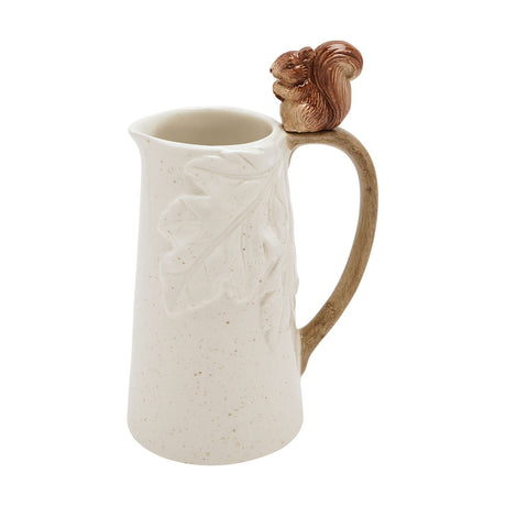 Cream ceramic jug with embossed oak leaf design and a speckled glaze, featuring a brown squirrel figure holding an acorn atop the curved handle, shown on a plain white background.