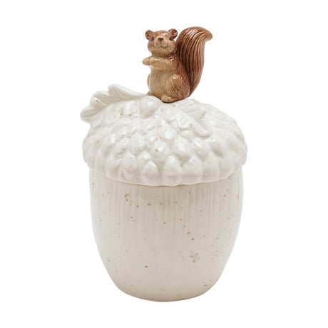 Cream ceramic acorn-shaped storage jar with ribbed body and scaled acorn-cup lid, topped with a brown squirrel figure, shown on a plain white background.