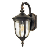 The Cleveland-2 Outdoor Small Wall Lantern in weathered bronze features a vintage-style design with a black finish, making it perfect as a small outdoor wall light. It comes with a clear glass shade that has a speckled texture for added antique charm. The visible bulb is mounted on decorative backing with intricate design accents and an IP44 rating ensures its durability.