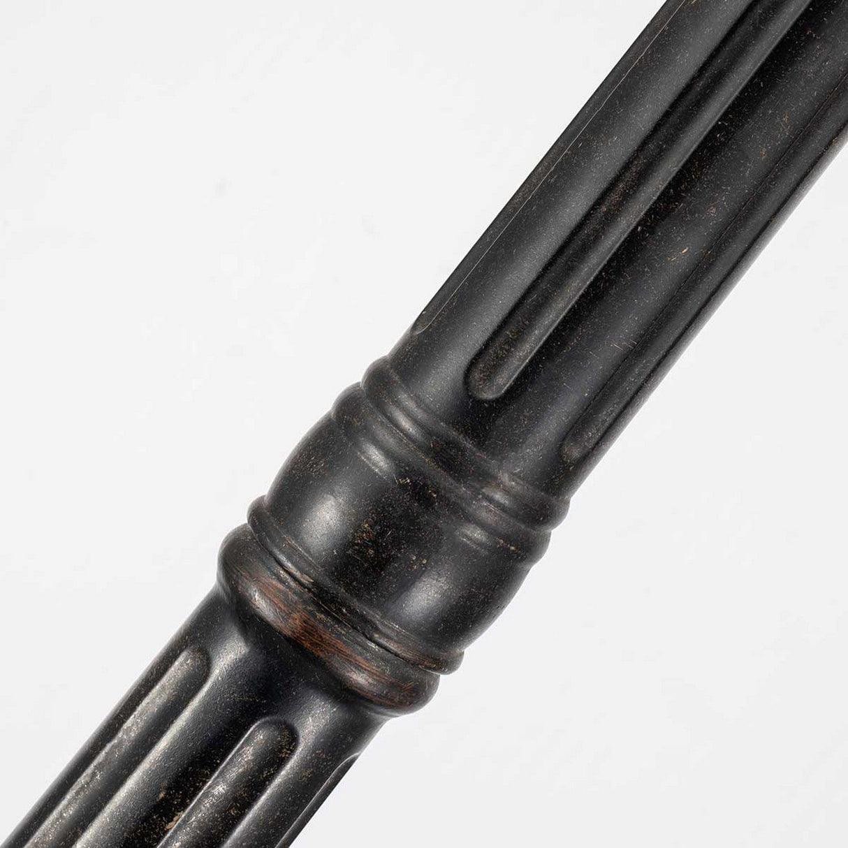 A close-up of a dark metal rod showcases its grooved, ridged texture against a plain white background. Reminiscent of the sleek design of the Cleveland Single Head Lamp Post in Weathered Bronze, it features circular bands and a smooth finish, perfect for enhancing any outdoor lighting setup.