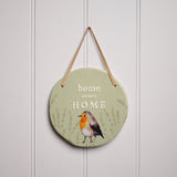 Round green ceramic hanging plaque with "home sweet HOME" raised lettering, a watercolour robin among lavender sprigs, and a suede hanging strap, shown on a white panelled wall.