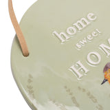 Close-up of the Robin and Lavender round ceramic hanging plaque in sage green, showing raised "home sweet HOME" lettering, a leather hanging strap, and faint lavender sprigs.