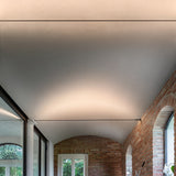 Clarionis 8mm LED strip holder in black, installed as a taut ceiling band illuminating a vaulted hallway with exposed brick arches.