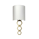 The Clark Small Wall Light - Aged Brass boasts a wall-mounted design, complete with a cylindrical faux silk shade and an elegantly decorative aged brass geometric support embellished with three connected hexagons.