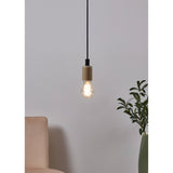 Clear LED GLS bulb with visible filaments, E27 cap, hanging lit from a black pendant cord against a light grey wall in a living room setting.