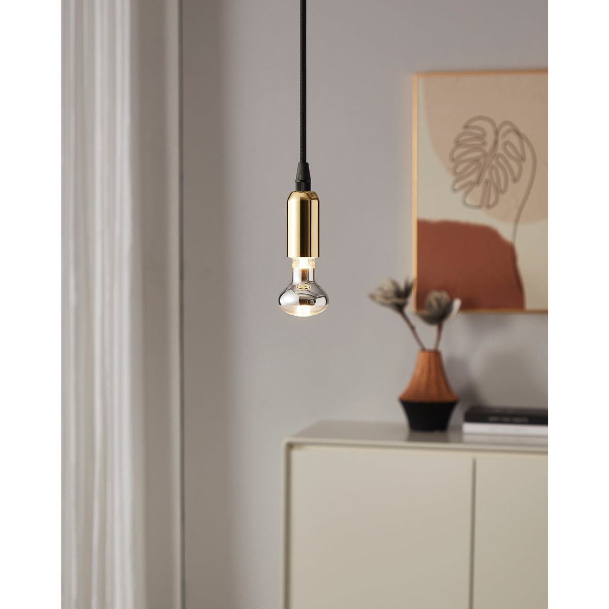 Clear Dimmable LED Reflector Bulb E14 R50 lit in a brass pendant fitting, shown hanging in a neutral living room with sideboard and wall art.