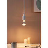 Clear dimmable LED reflector bulb E27 with mirrored silver dome, shown lit in a white pendant fixture above a table set with candles and a mug.