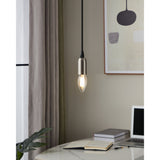 Clear LED candle bulb with E14 fitting glowing warm white in a brushed metal pendant light above a desk setting.