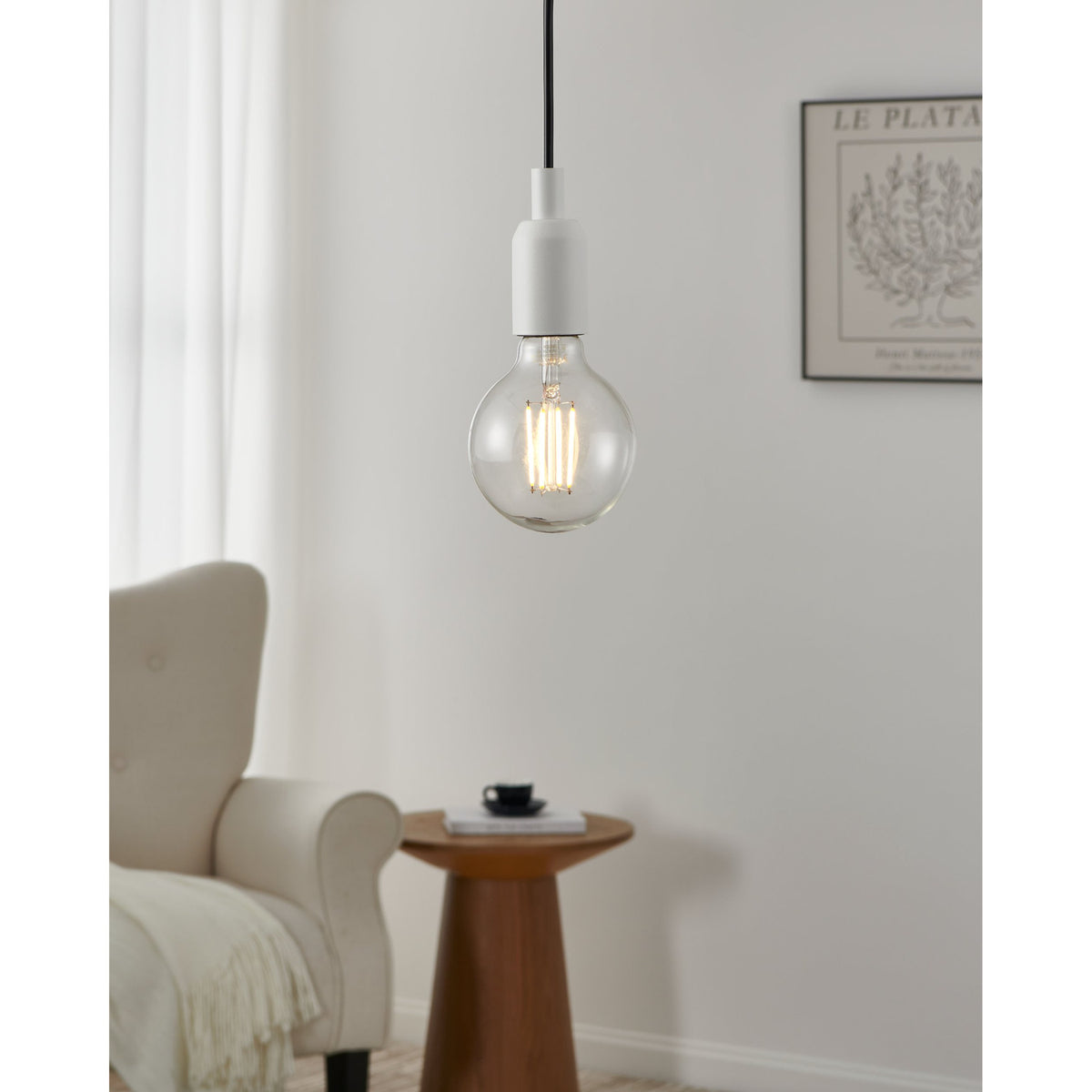 Clear LED globe bulb (E27, G95, 8W, warm white) with visible upright filaments, fitted to a white pendant hanging in a living room beside an armchair and side table.