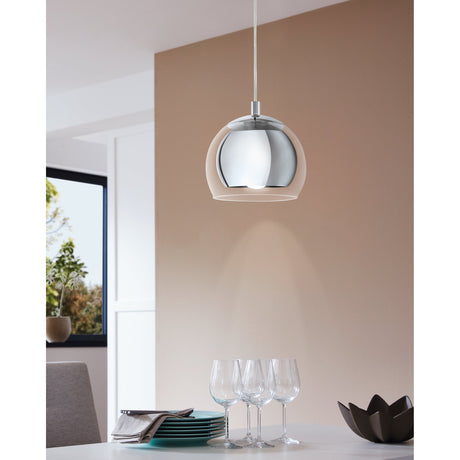 Clenette Clear Glass Pendant Light in Chrome hanging above a dining table with glassware, featuring a domed clear glass shade around a mirrored chrome inner globe.