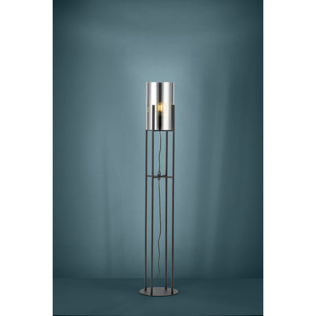 Clisvelle Floor Lamp in black steel, featuring four slim upright rods on a round base supporting a cylindrical vaporised glass shade with a visible E27 bulb, shown against a teal studio background.