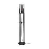 Clisvelle Floor Lamp in black steel with a tall four-rod frame, round base, and cylindrical black-transparent glass shade, shown on a plain white background.
