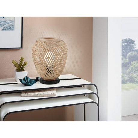 Clivorne Table Lamp in Black with a rounded open-weave wood shade and round black steel base, shown lit on a console table in a living room setting.