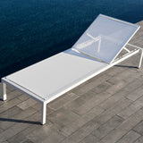 Club Aluminium Sun Lounger Frame with Wheels in white, reclined backrest and sling seat on a stone poolside deck beside dark water.