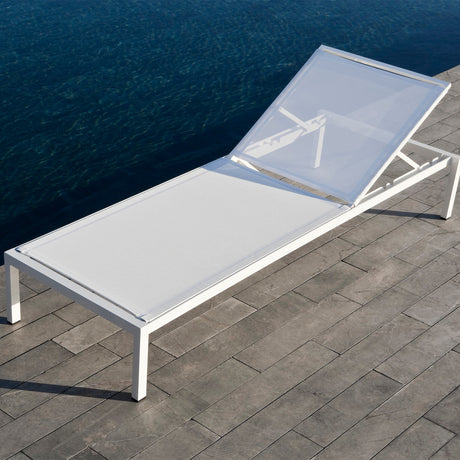 Club Aluminium Sun Lounger Frame with Wheels in white, reclined backrest and sling seat on a stone poolside deck beside dark water.