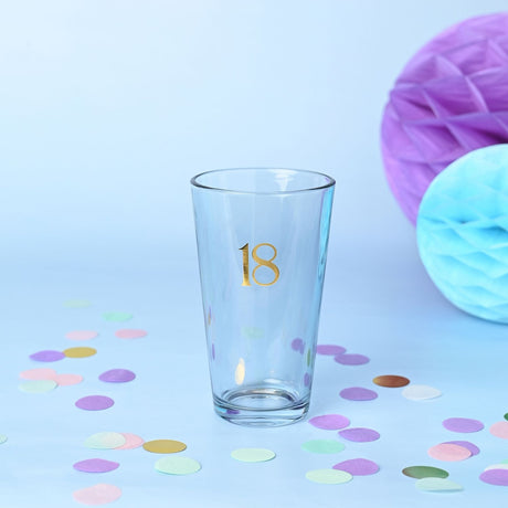Clear tapered beer glass, 460ml, with gold foiled "18" on the front, set against a light blue background with pastel confetti and honeycomb decorations.