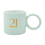 Matt porcelain mug in pale light blue with a gold serif "21" and round ring handle, striped green and blue interior, shown on a plain white background.
