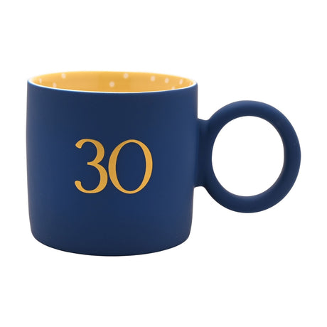 Navy matt porcelain mug with gold "30" numeral, round ring-shaped handle, and a yellow polka-dot interior, shown on a plain white background.