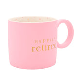 Happily Retired matt porcelain mug in pink with gold lettering, round ring handle, and a speckled cream interior, shown on a plain white background.