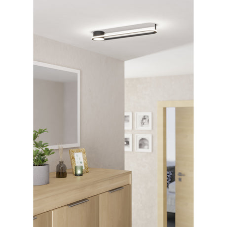 Collecorvino LED Flush Ceiling Light in black, an oval track-shaped aluminium and steel fixture with a white diffuser edge, shown mounted in a hallway above a wooden sideboard.